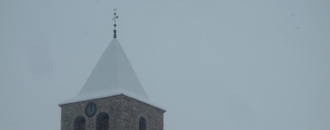 Agulla i rellotge del campanar de Santa Eulàlia de Pi sota una nevada